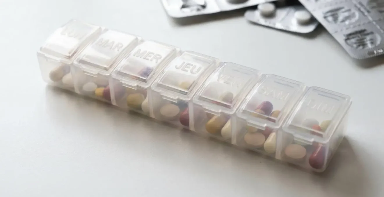 Pilulier hebdomadaire organisé avec médicaments quotidiens sur surface médicale blanche